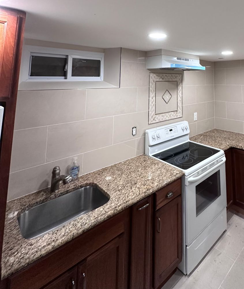 Finished kitchen with large-format wall tile, granite counters and a tile medallion behind the range