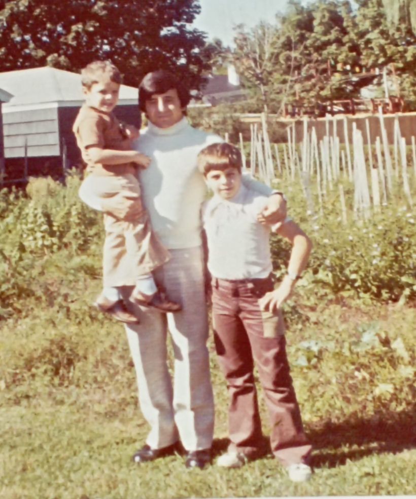 My uncle standing in a garden, holding my brother and me