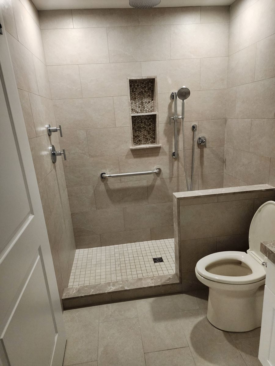 Remodeled bathroom with large stone-look wall tile, a curbed walk-in shower, mosaic floor and a recessed niche