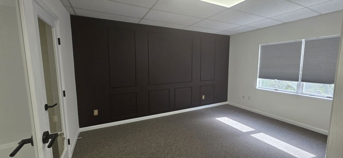 Office with a deep brown accent wall trimmed in picture-frame panel moulding