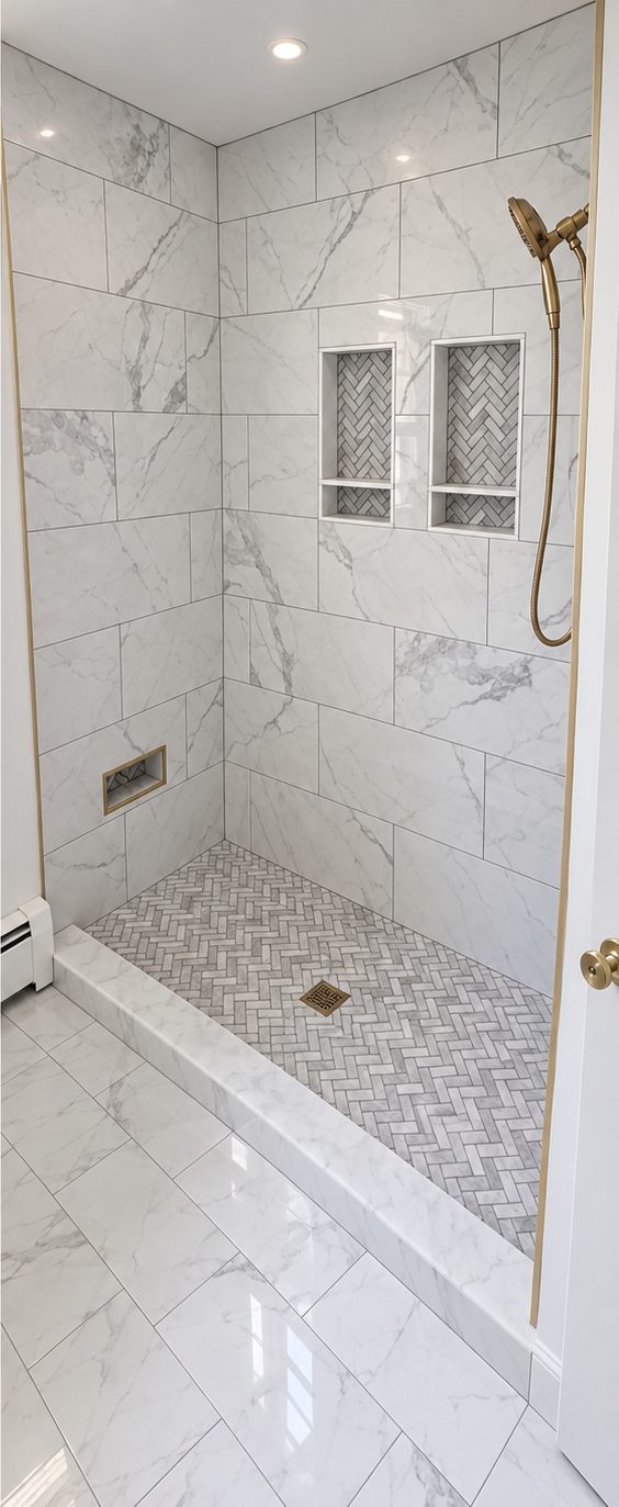 Walk-in shower with large white veined wall tile, two recessed niches and a herringbone mosaic floor